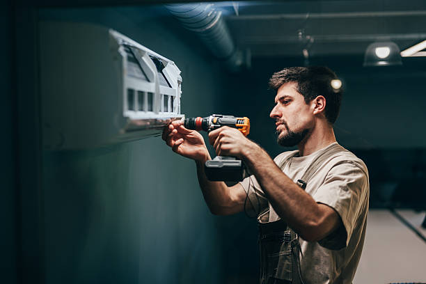istock Man installs wall-mounted shelf in a modern indoor space using a power drill 2218236490