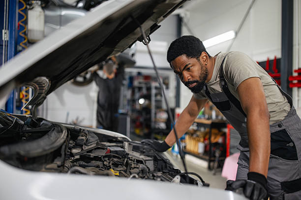A focused mechanic closely examining details of a vehicle's engine, embodying dedication and professionalism in automotive diagnostics and repair within a well-equipped workshop.
