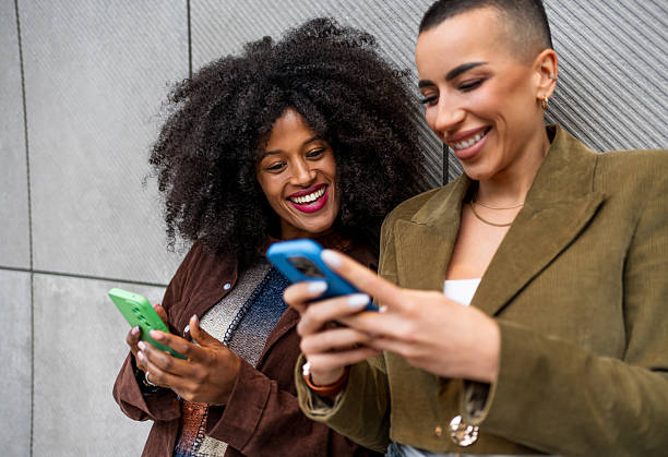 istock Two young women using mobile phones and smiling 2218237652
