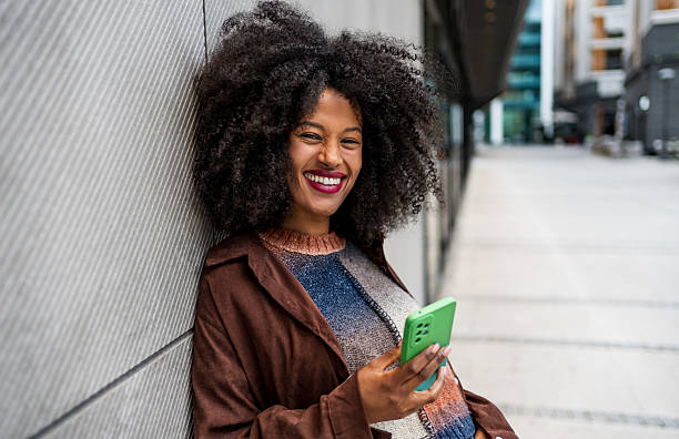 istock Smiling young woman using mobile phone in the city 2218238963