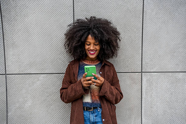 istock Young woman using mobile phone leaning against a wall 2218239722