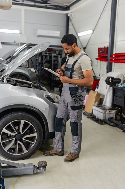 istock Mechanic Inspecting Vehicle Engine by Checklist 2218239990