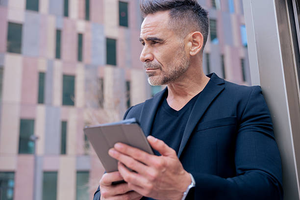 istock Businessman using tablet and looking away in modern city, outdoor technology use 2218240152