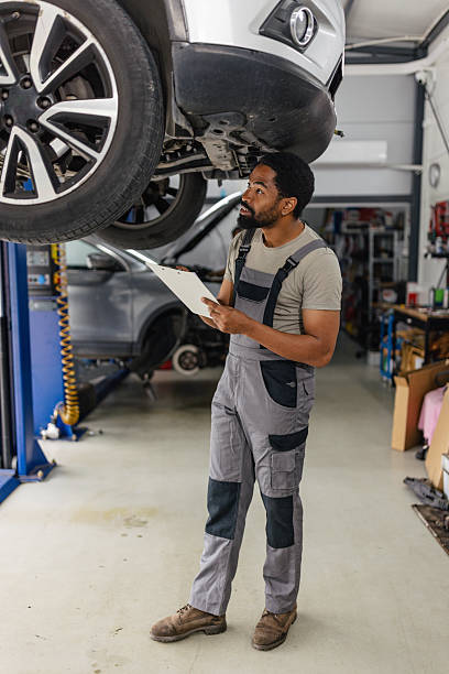 istock Mechanic Inspecting Car Under Lift in Workshop 2218241230