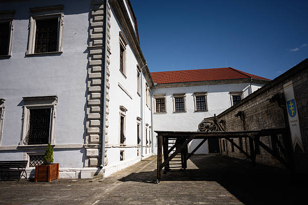 Zbarazh, Ukraine - May 30, 2025: A courtyard Zbarazh castle with historic white buildings, wooden wagon, and bright sunny atmosphere.