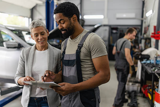 istock Mechanic Explains Car Issues to a Client in Garage 2218241787