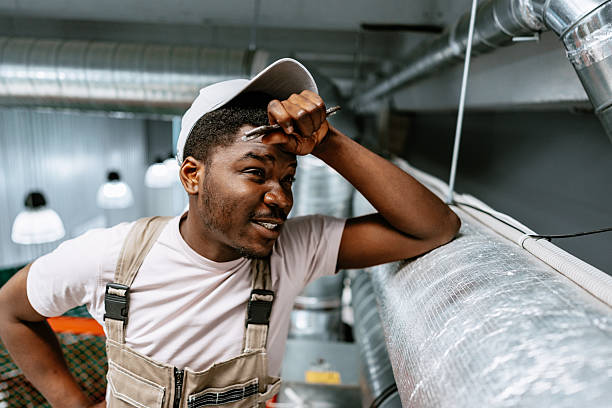 istock Worker assesses air duct installation in industrial space during daylight hours 2218242319