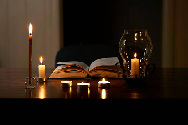 istock Book and burning candles on table in dark room 2218245931