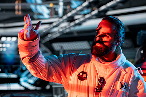 Space crew member responds to alien hostile presence red light alert during mission. Astronaut raises hand instinctively as unseen extraterrestrial form attacker approaches in orbital station cockpit
