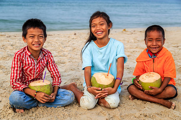 istock Cambodian children holding coconuts on the beach, Cambodia 2218250195