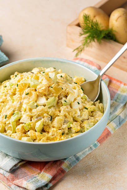 istock Vertical image of Potato salad made from boiled potatoes, boiled eggs, onions, celery, mustard, pickle, mayonnaise and paprika dressing. 2218250247