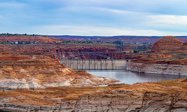 A striking view of Glen Canyon Dam with its impressive concrete structure framed by the surrounding red rock formations. The dam holds back the waters of Lake Powell, a vital reservoir in the arid landscape of the American Southwest.