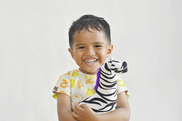 3 year old southeast asian child hugging doll smiling on white background