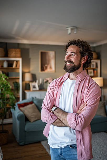 istock Happy man smiling and looking away while standing at home 2218255385