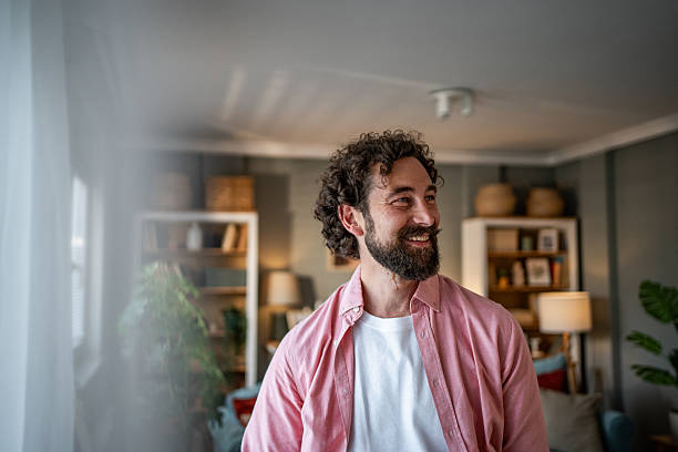 istock Happy man smiling and looking away while relaxing at home 2218255439