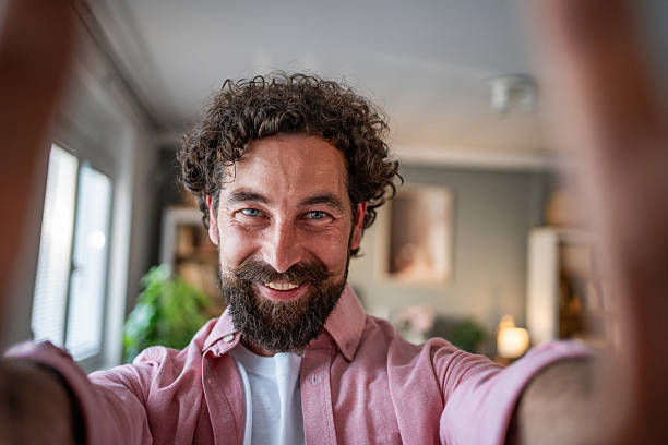 istock Happy man taking a selfie at home with smartphone 2218255475