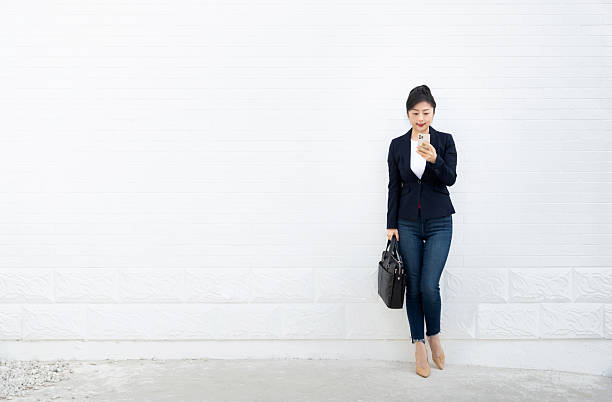 istock Smiling woman using mobile phone in front of white wall 2218255958