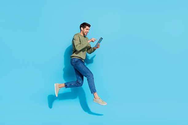 istock Full size portrait of sportive active person hold ereader write message jump isolated on blue color background 2218257624