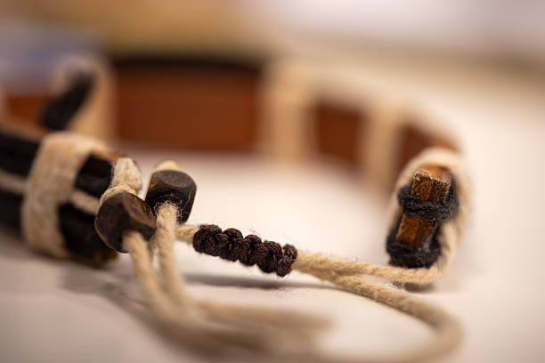 Close-up of a handmade leather bracelet with woven rope detailing placed on a white surface. The rustic craftsmanship and natural texture of the materials, ideal for themes related to fashion accessories. Selective focus