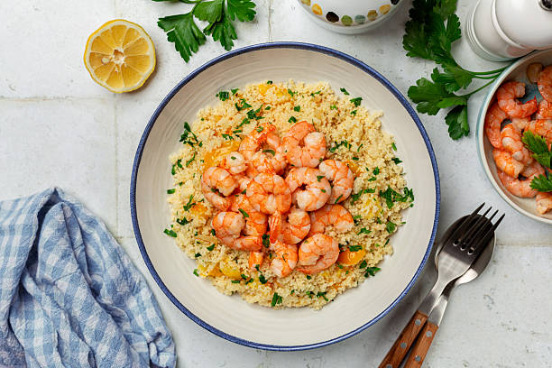 istock Mediterranean Couscous with fried Shrimps, yellow tomatoes, onion, parsley. White table surface. Top view. 2218264204