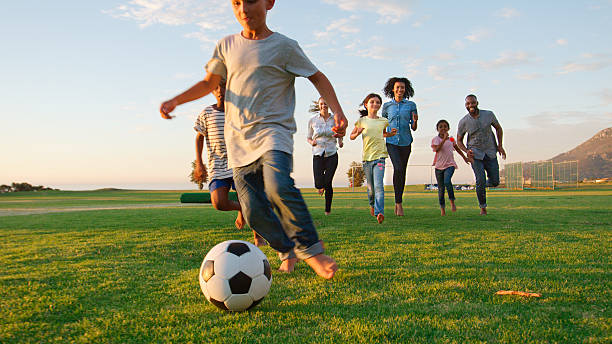 istock Multi Cultural Families Having Fun Playing Soccer In Park With Evening Light 2218265554