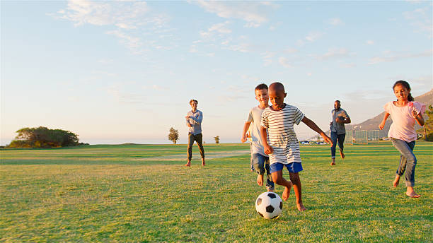 istock Multi Cultural Families Having Fun Playing Soccer In Park With Evening Light 2218265559
