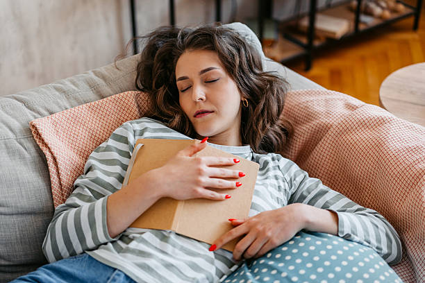 istock Young Woman Falling Asleep On The Sofa While Reading A Book 2218267263