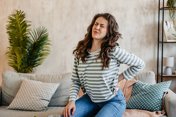 istock Young Woman Having Back Pain While Sitting On The Sofa At Home 2218267714