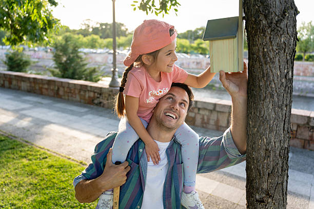 istock Father helping daughter mount a birdhouse on a tree on a sunny day 2218273406