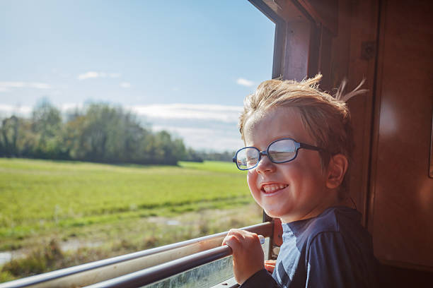 istock Boy leans from carriage window taking in green fields passing by 2218275949
