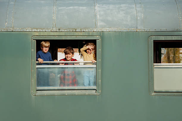 Three young passengers gaze out excitedly from a green trains window having fun trip on their vacations