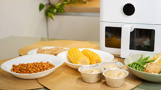 istock Air fryer cooking various dishes including corn, muffins, and vegetables 2218277050