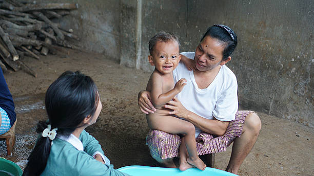 A toddler is held firmly by adults while crying during a bath, expressing emotional discomfort and fear of water.