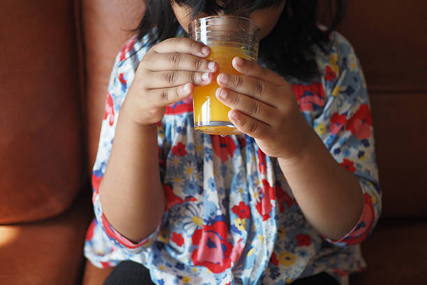 istock Kid enjoys fresh juice while sitting on a couch 2218279622