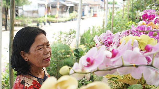 istock Happy Elderly Woman Among Blooming Orchids 2218279713