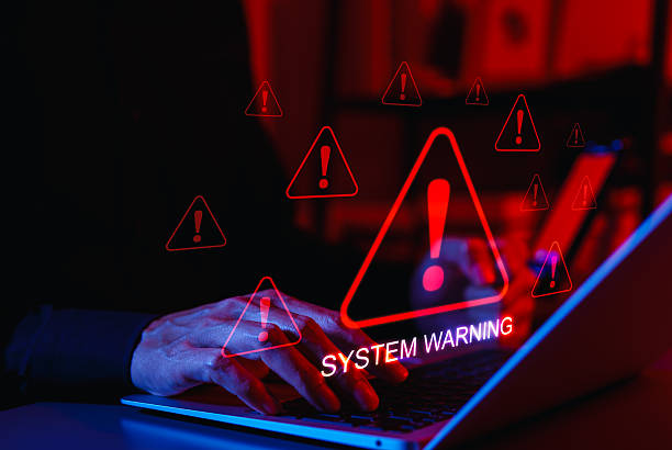 istock System Warning Alert and Cybersecurity Threat Concept. A person using laptop with system warning and exclamation triangles red, symbolizing cyber security alerts, system failure, and critical threats. 2218279735
