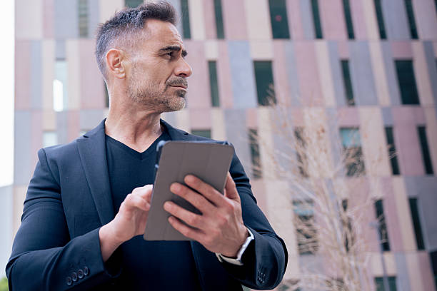 istock Businessman using tablet and looking away in modern city, outdoor technology use 2218284651