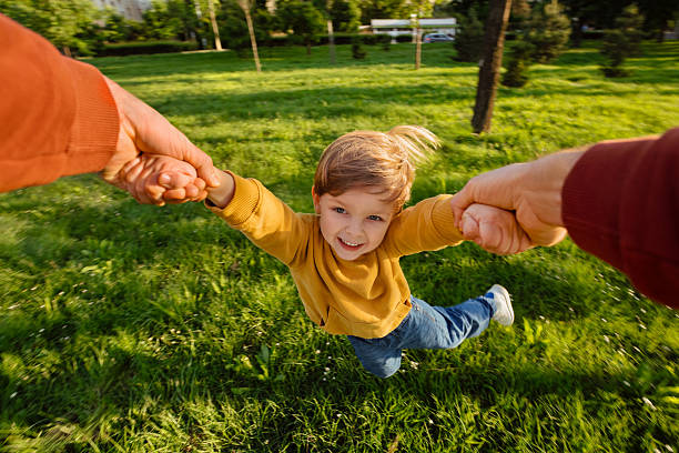 istock Child Spinning Joyfully with Parents in Park 2218285233
