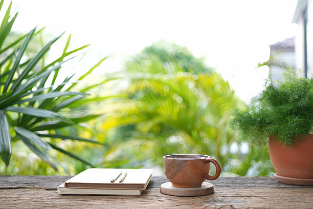 A wooden teacup and an old notebook set against a cozy gardening backdrop