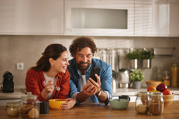istock Happy couple enjoying breakfast and browsing social media on smartphone in kitchen 2218291318