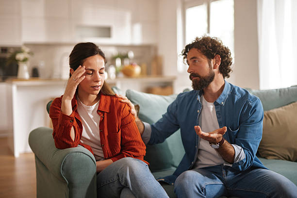Young couple having relationship problems sitting on sofa at home