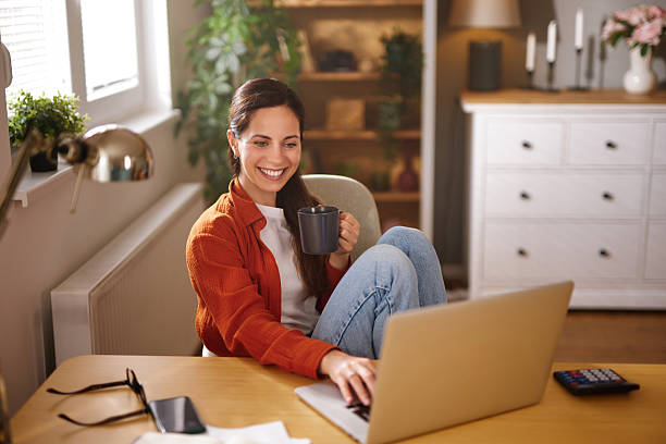 istock Young woman working from home, drinking coffee and using laptop 2218292007