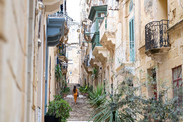 Young woman walks steps in colourful, narrow streets in old town, Birgu, Valetta