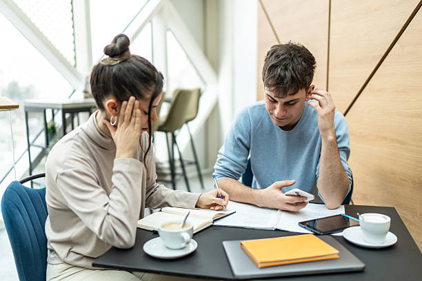 istock Two young adults studying and working together in a modern cafe 2218292881