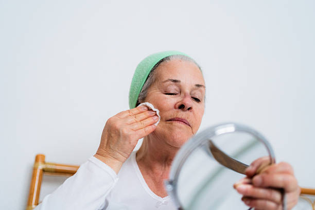 istock Senior woman removing makeup with cotton pad and mirror 2218293485