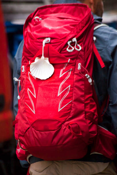 Rear view of man pilgrim in the 'camino de santiago', large backpack and scallop shell symbol . Santiago de Compostela, Galicia, Spain.