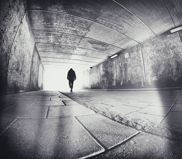 istock Man in silhouette walking in urban concrete tunnel. 2218300044