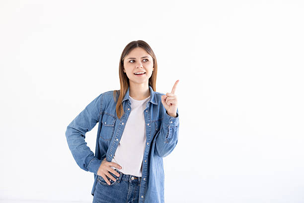 istock Smiling woman pointing finger up over white background 2218300159