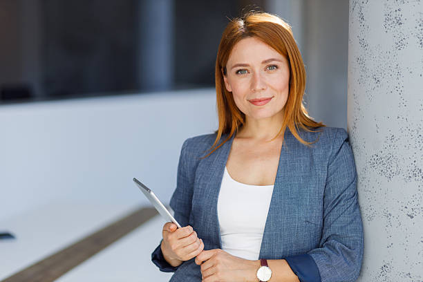 istock Professional businesswoman analyzing digital tablet, smiling confidently within sleek corporate workspace 2218301916