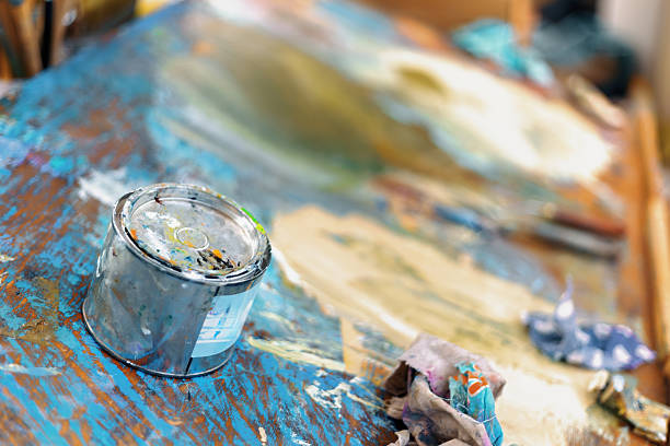 Paint can sits on an artist's messy workbench in a studio